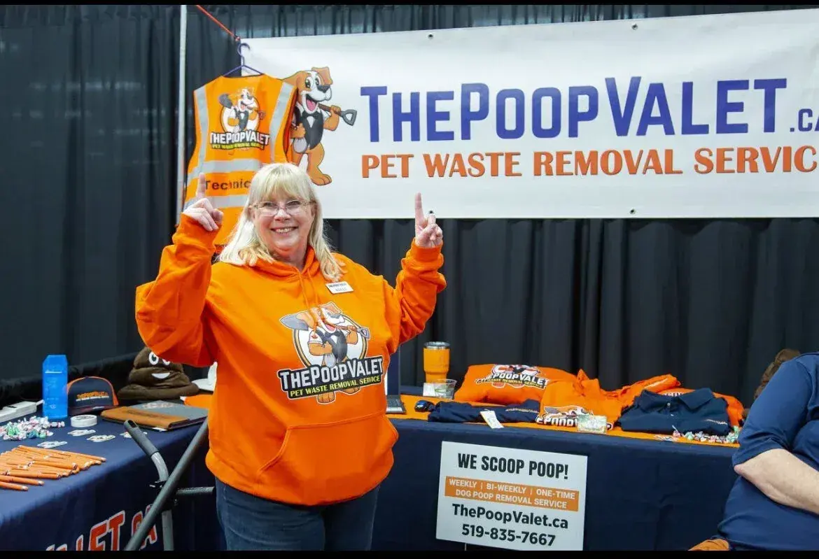 A Poop Valet team member in an orange hoodie at a community event booth